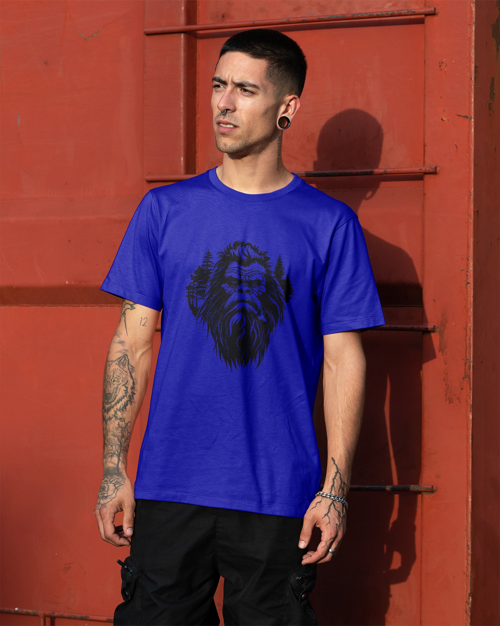 Person wearing a t-shirt featuring a stylized Bigfoot face with pine trees forming part of the wilderness design.