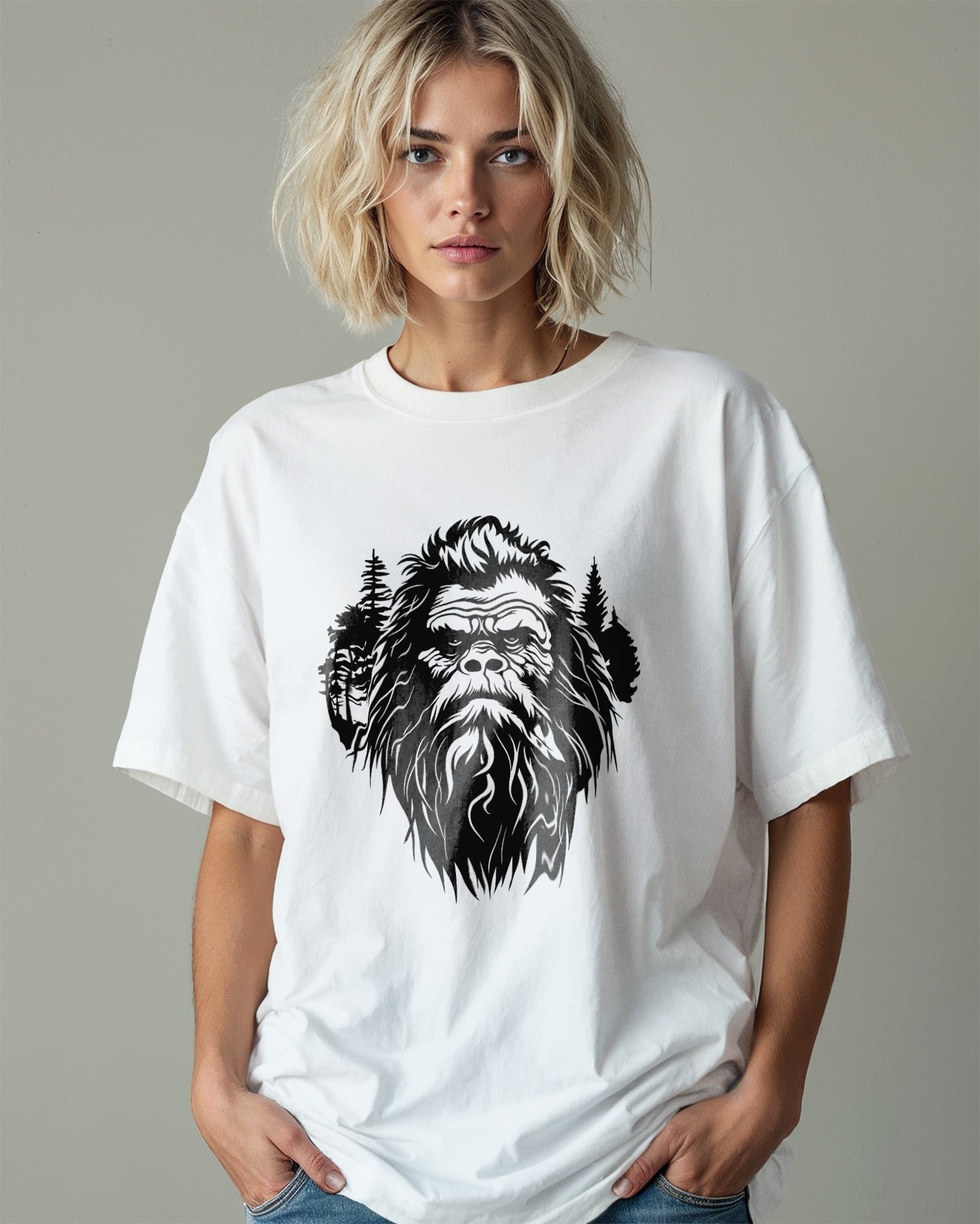 Person wearing a t-shirt featuring a stylized Bigfoot face with pine trees forming part of the wilderness design.