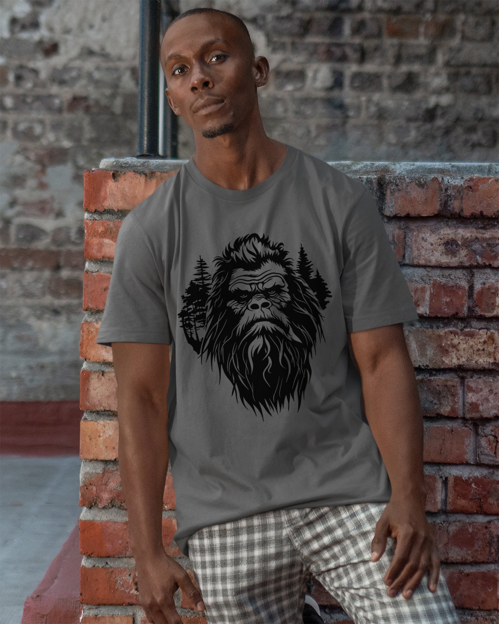 Person wearing a t-shirt featuring a stylized Bigfoot face with pine trees forming part of the wilderness design.