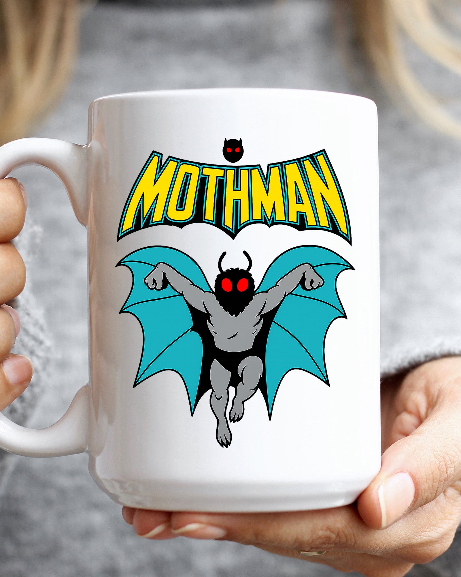 Ceramic mug featuring a cartoon-style Mothman with glowing red eyes and wings under the word MOTHMAN.