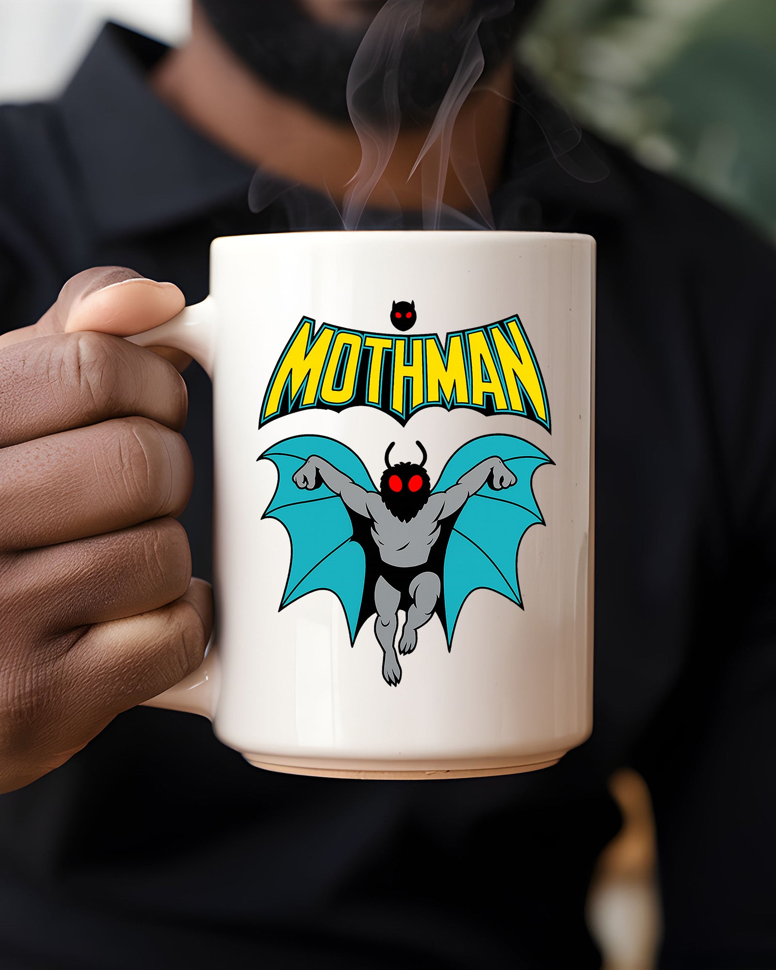 Ceramic mug featuring a cartoon-style Mothman with glowing red eyes and wings under the word MOTHMAN.