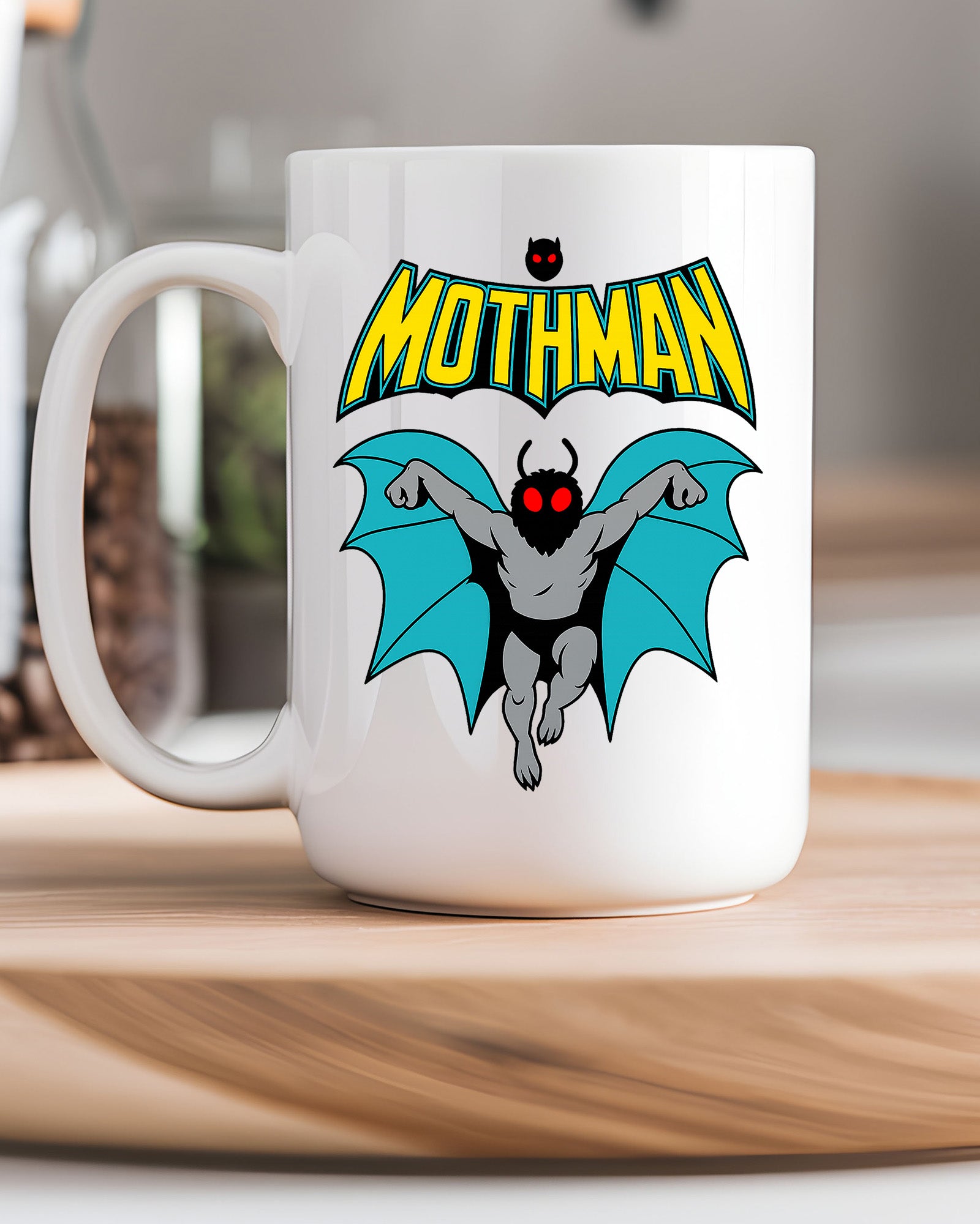 Ceramic mug featuring a cartoon-style Mothman with glowing red eyes and wings under the word MOTHMAN.