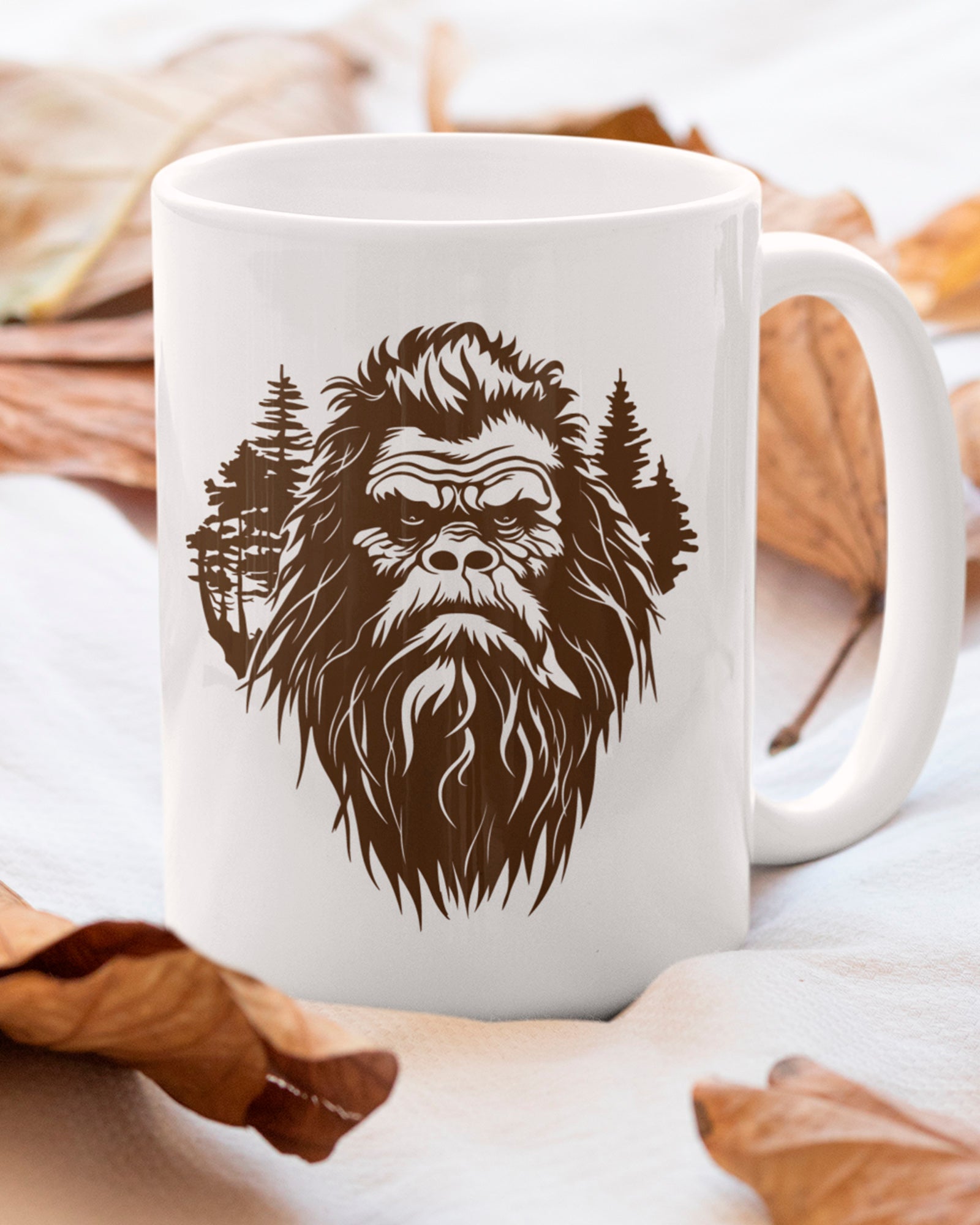 Ceramic mug featuring a stylized Bigfoot face with pine trees forming part of the wilderness design.